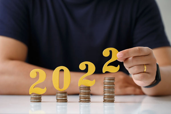 Man placing numbers 2022 on stacks of coins from local federal credit union